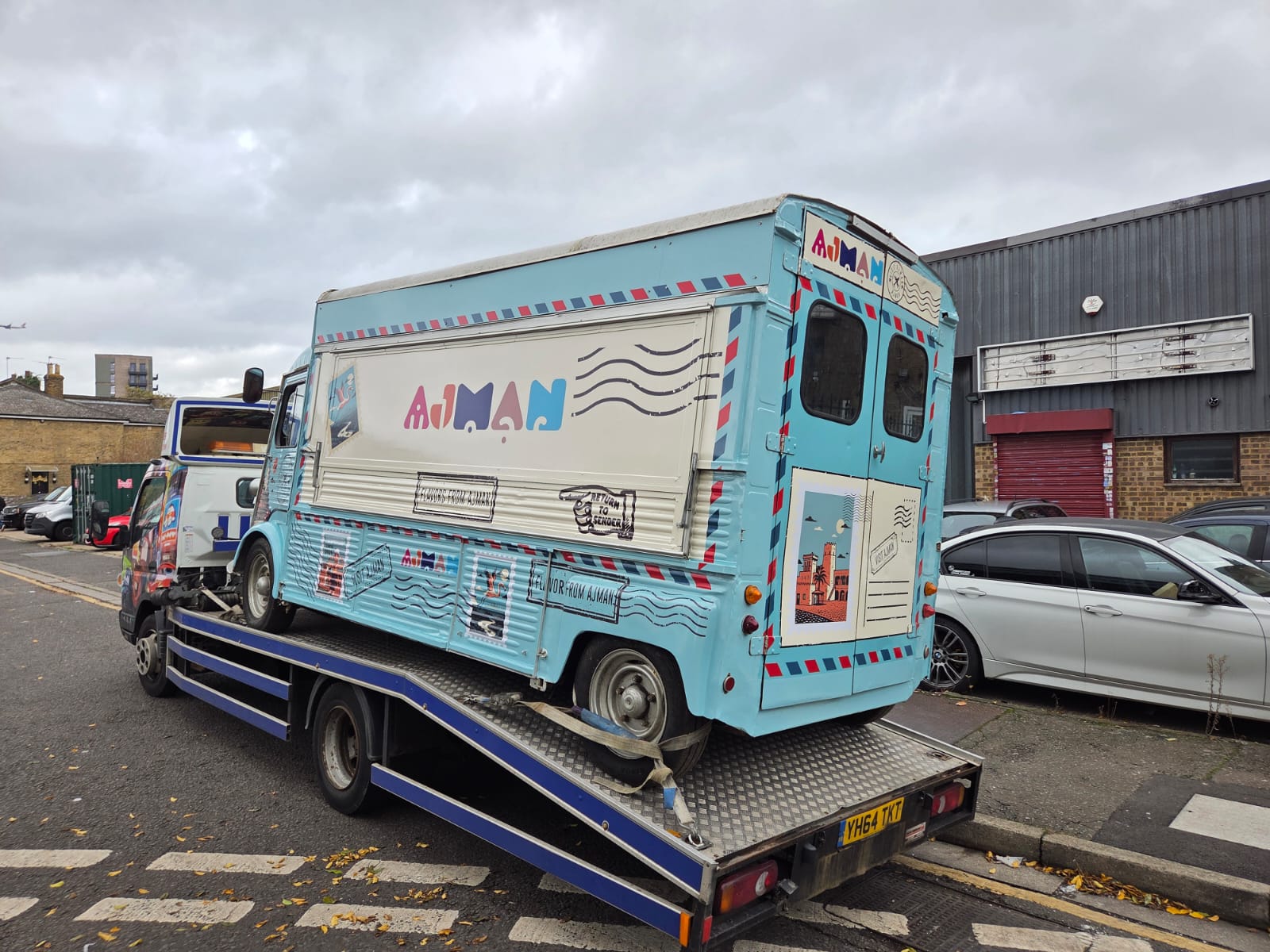 Pale-blue vintage Ajman food truck with airmail-style graphics