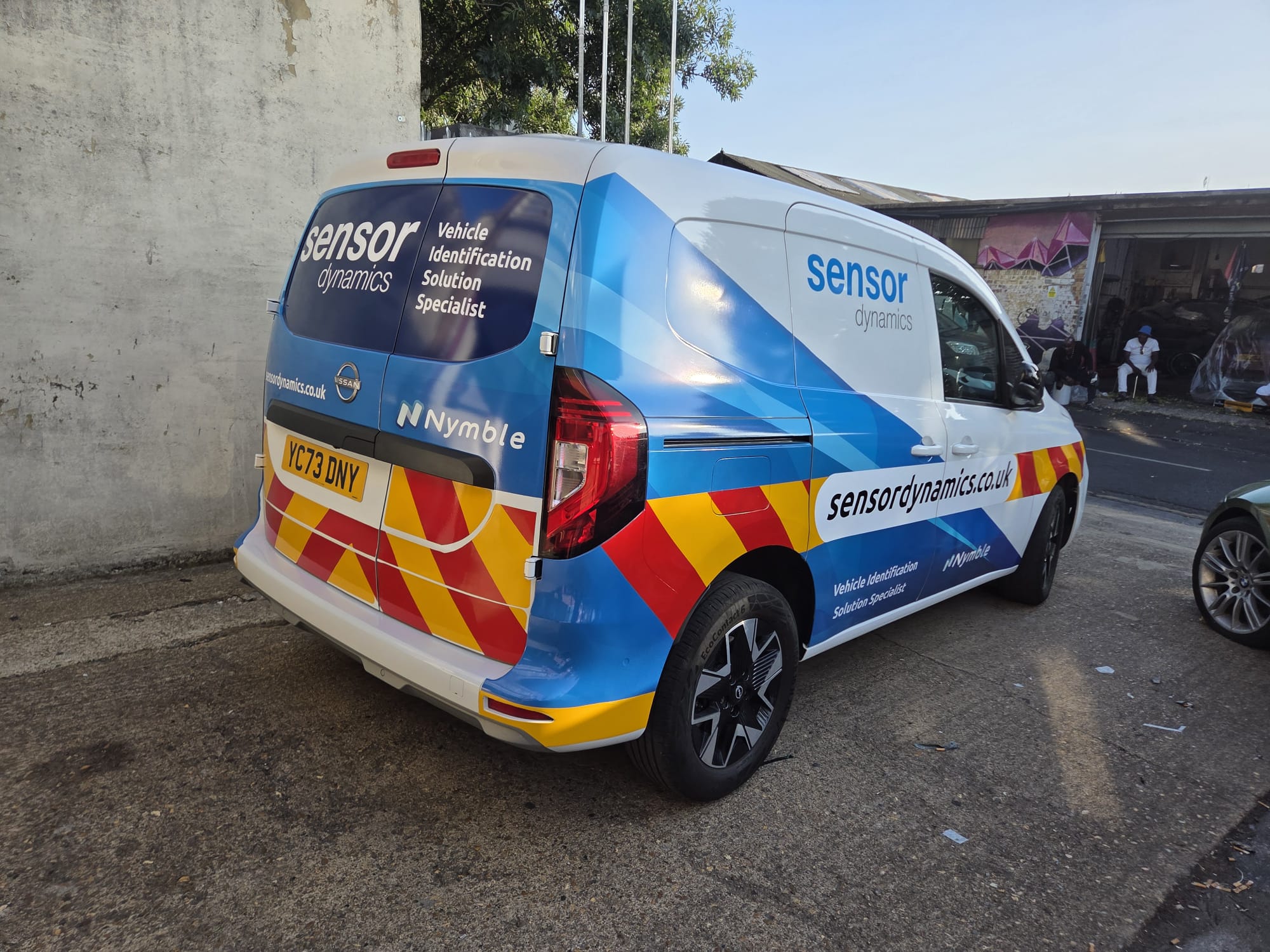 Sensor Dynamics van with blue wrap and red and yellow chevrons